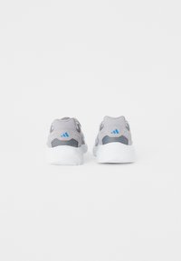 Zapatillas deportivas grises con paneles de malla, acentos azules y una suela blanca, que presentan una forma redondeada y un diseño minimalista.