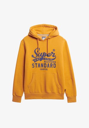 Geel hoodie van zacht materiaal, met een voorzak in kangoeroestijl, een capuchon met trekkoord en bedrukt tekst in marineblauw.