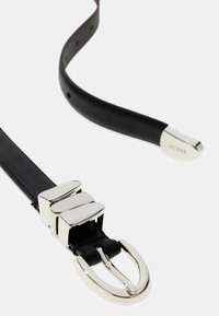 Curea din piele neagră cu o cataramă din metal argintiu care are trei accente dreptunghiulare. Capătul are un finisaj lustruit cu numele mărcii embossat.