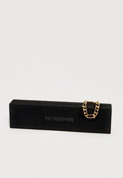 Pulsera de cadena de oro descansando sobre una caja rectangular de terciopelo negro con la marca "PATTARAPHAN" en el frente.