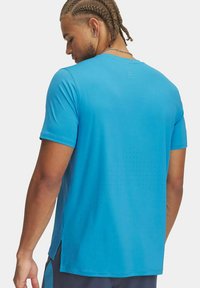 Camiseta deportiva azul de manga corta, con una textura transpirable y pequeñas perforaciones en la parte posterior para ventilación.