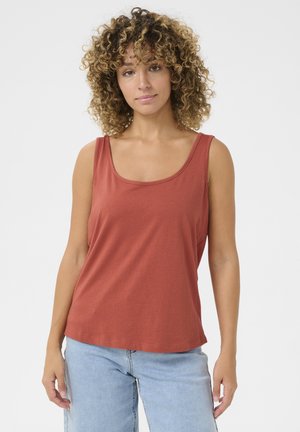 Eisenrote Tanktop mit Rundhalsausschnitt und weiten Armausschnitten, aus weichem Stoff gefertigt. Kombiniert mit hellblauen Jeans.