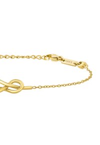 Pulsera de oro con un diseño de nudo retorcido, cadena enlazada y un cierre de langosta con una etiqueta de marca. Acabado suave, textura brillante.