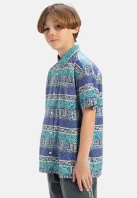Korte mouwen shirt met een geometrisch patroon in tinten blauw, paars en wit. Gemaakt van lichtgewicht stof met een knoopsluiting.