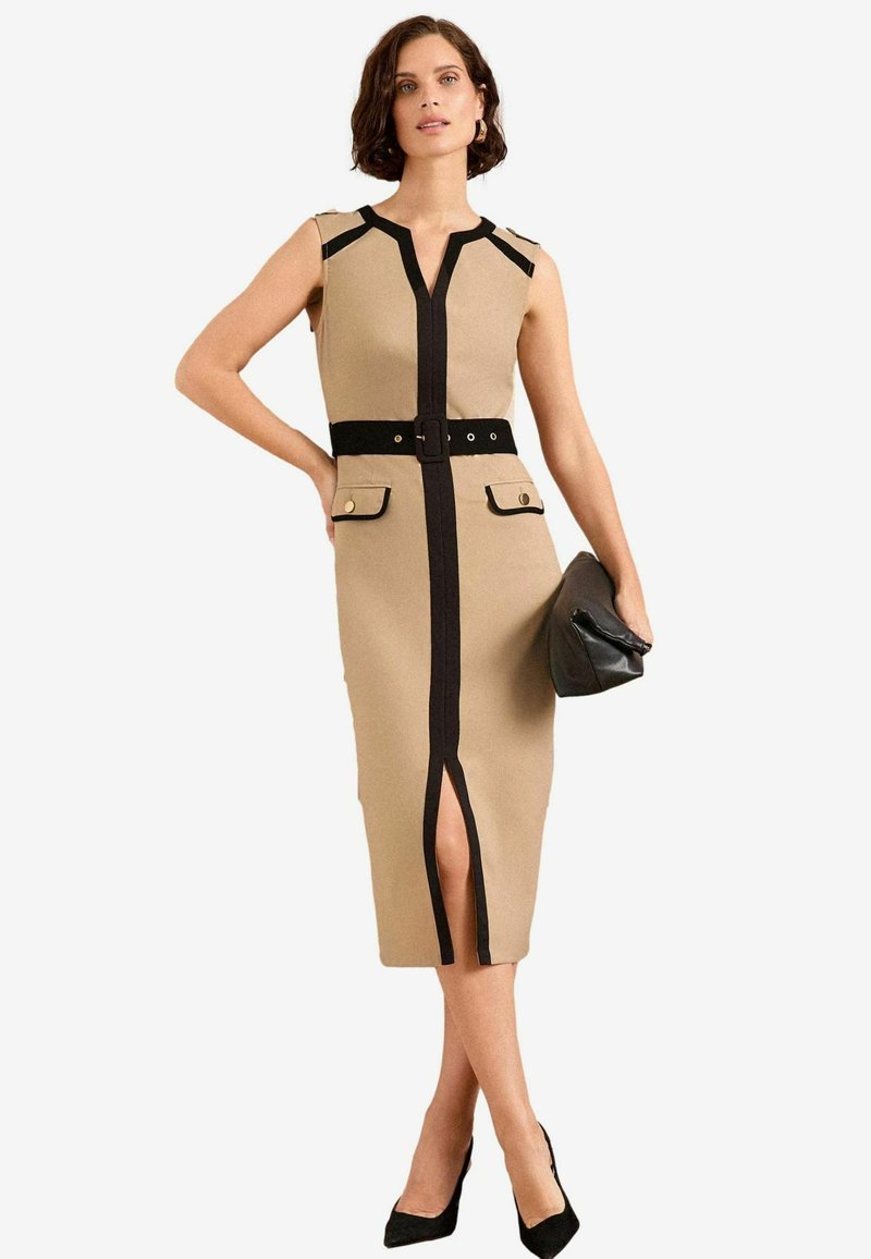 Beige mekko polvipituudella, mustilla yksityiskohdilla, hihaton malli, V-pääntie, etuaukko, vyöllinen vyötärö ja kaksi etutaskua. Musta clutch-laukku ja korkokengät.