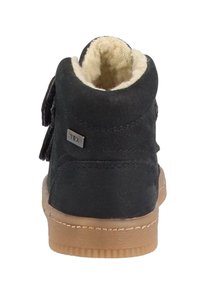 Μαύρο σουέτ μποτάκι αστραγάλου με απαλό κρεμ φόδρα, καφέ καουτσούκ σόλα και διακοσμητικό πλάγιο κούμπωμα. Διαθέτει μία μικρή μεταλλική ετικέτα.