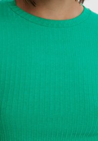 Top a coste verde con scollatura rotonda, caratterizzato da righe verticali e una texture liscia. La vista ravvicinata mette in evidenza i dettagli del tessuto.