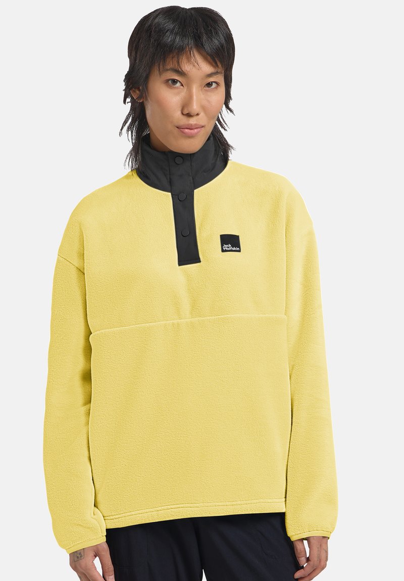 Pullover in pile giallo con colletto a metà zip nera, bottoni a pressione e una piccola etichetta con logo sul davanti. Tessuto morbido e vestibilità comoda.