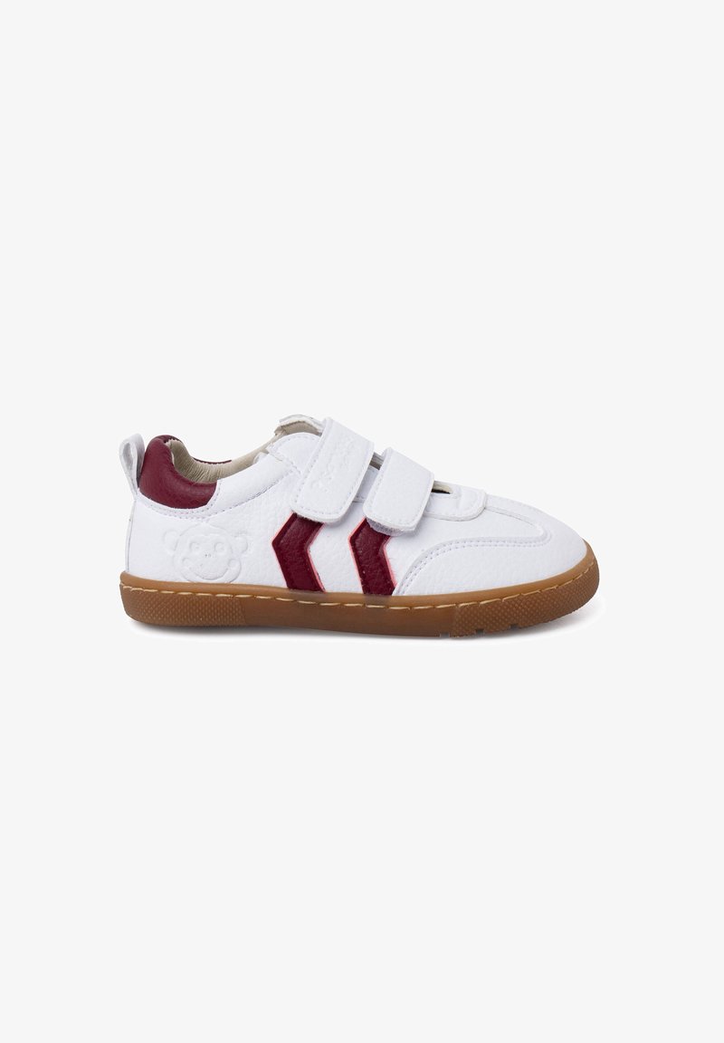 Baskets blanches en cuir avec des accents rouges et des bandes Velcro. Elles présentent une surface texturée, une semelle en caoutchouc marron et un petit design embossé.