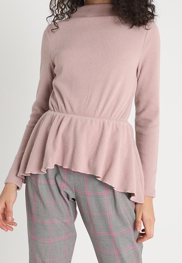 Helle rosa gerippte Langarmbluse mit einem Peplum-Saum, kombiniert mit grauen karierten Hosen mit pinken Akzenten. Weiche Textur, tailliert.