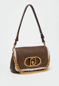 Sac à main en daim marron avec bordure en shearling blanc, détail de chaîne dorée et grand fermoir ovale doré sur le rabat avant.
