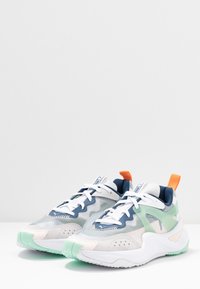 Lätta sneakers med en blandning av grå, vit och marinblå mesh och syntetiska material. Har en mintgrön sula och en orange hältab.