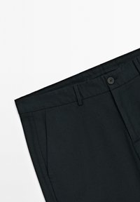 Černé kalhoty na míru vyrobené z hladké látky, s plochým předním dílem, poutky na opasek a jedním knoflíkem, s bočními kapsami.