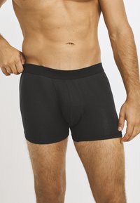 Black, ribbed boxer shorts with a wide elastic waistband and contoured pouch. The fabric appears soft and closely fitted.