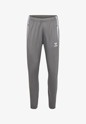 Szare sportowe spodnie dresowe z elastycznym pasem, bocznymi kieszeniami na zamek, białymi paskami po bokach oraz logo Hummel na górnej części uda.