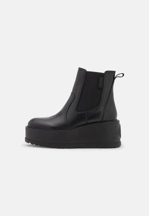 Black leather platform ankle boot with elastic side panels and pull tab, smooth finish, and thick ridged sole.
