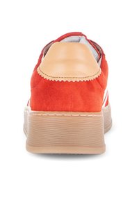 Rode suède sneaker met een tan leren hielkap, gestructureerde rubberen zool en witte stiksels langs de basis, met een laag profiel ontwerp.