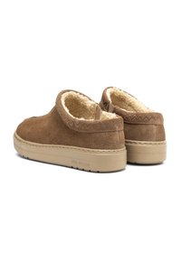 Brązowe zamszowe buty typu slip-on z miękkim futerkiem z materiału sztucznego, zaokrąglonym tyłem i jasnobrązową gumową podeszwą, z dekoracyjnym przeszyciem na wierzchu.
