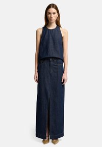 Ensemble en denim comprenant un haut sans manches et une longue jupe avec une fente avant, tous deux en denim de teint foncé. Tissu texturé et coupe droite.