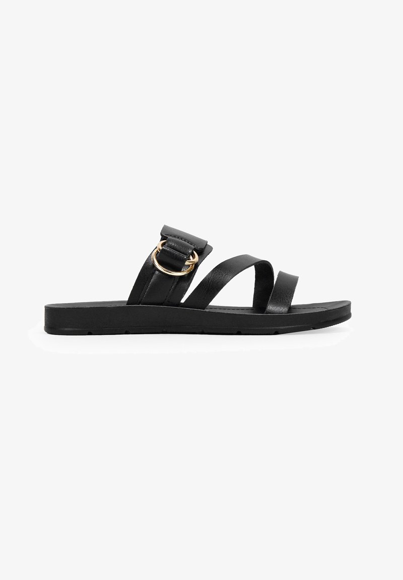 Sandal in pelle nera con due ampie cinghie, una decorata con un anello dorato. Suola piatta, design minimalista e texture liscia.
