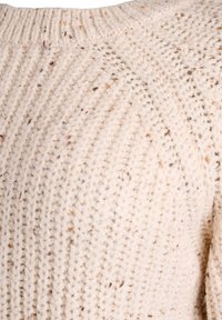 Krémový pletený sveter s ribovanou textúrou, so škvrnami hnedej a béžovej farby. Okrúhly výstrih a pohodlný dizajn.