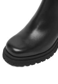 Czarny skórzany botek za kostkę z zaokrąglonym noskiem i teksturowaną gumową podeszwą, z gładką cholewką i lekko podniesioną krawędzią dla stabilności.