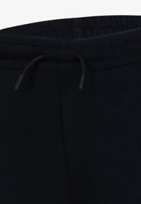 Czarne dresy z elastycznym paskiem z regulacją i czarnymi metalowymi końcówkami, miękka tekstura oraz dyskretne hafty wzdłuż krawędzi.