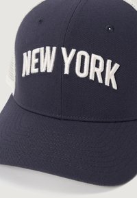 Jūras spēku baseball cepure ar baltu "NEW YORK" izšuvumu priekšpusē, ar teksturētu audumu un acs aizmuguri. Malas ir plašas un plakanas.