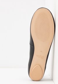 Semelle d'une chaussure plate noire avec semelle en caoutchouc beige montrant de fines lignes horizontales d'adhérence à l'avant et au talon, taille 37, de marque "Dynafit."