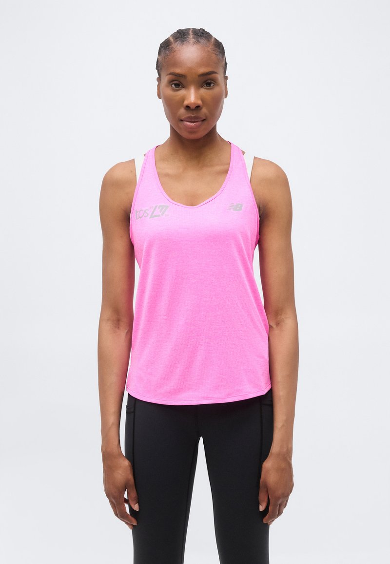 Γυναίκα με πλεξούδες, ντυμένη με φωτεινό ροζ αμάνικο αθλητικό τοπ και μαύρο κολάν, στέκεται μπροστά σε ένα απλό ανοιχτό φόντο.