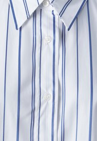 White button-up shirt featuring vertical blue stripes, classic collar, and button closures, made of a smooth, lightweight fabric.