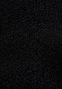 Primer plano de una tela negra texturizada con un sutil patrón tejido y fibras suaves y peludas que crean una superficie táctil.