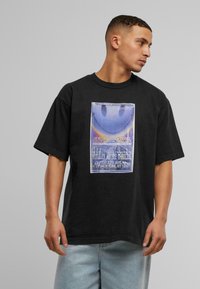 Svart bomulls T-skjorte med korte ermer, med et fargerikt grafisk trykk av et smilende ansikt og tekst i vintage-stil typografi.