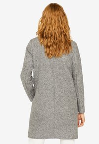 Abrigo de lana gris con corte recto, ajuste relajado y mangas largas. Presenta un detalle de costura en la parte posterior, adecuado para un uso casual.