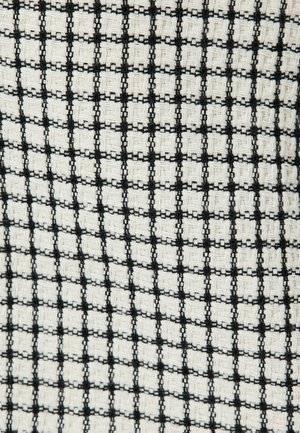 Tejido que presenta un patrón de cuadrícula en blanco y negro con cuadrados texturizados. El diseño muestra materiales tejidos alternos para un contraste visual.