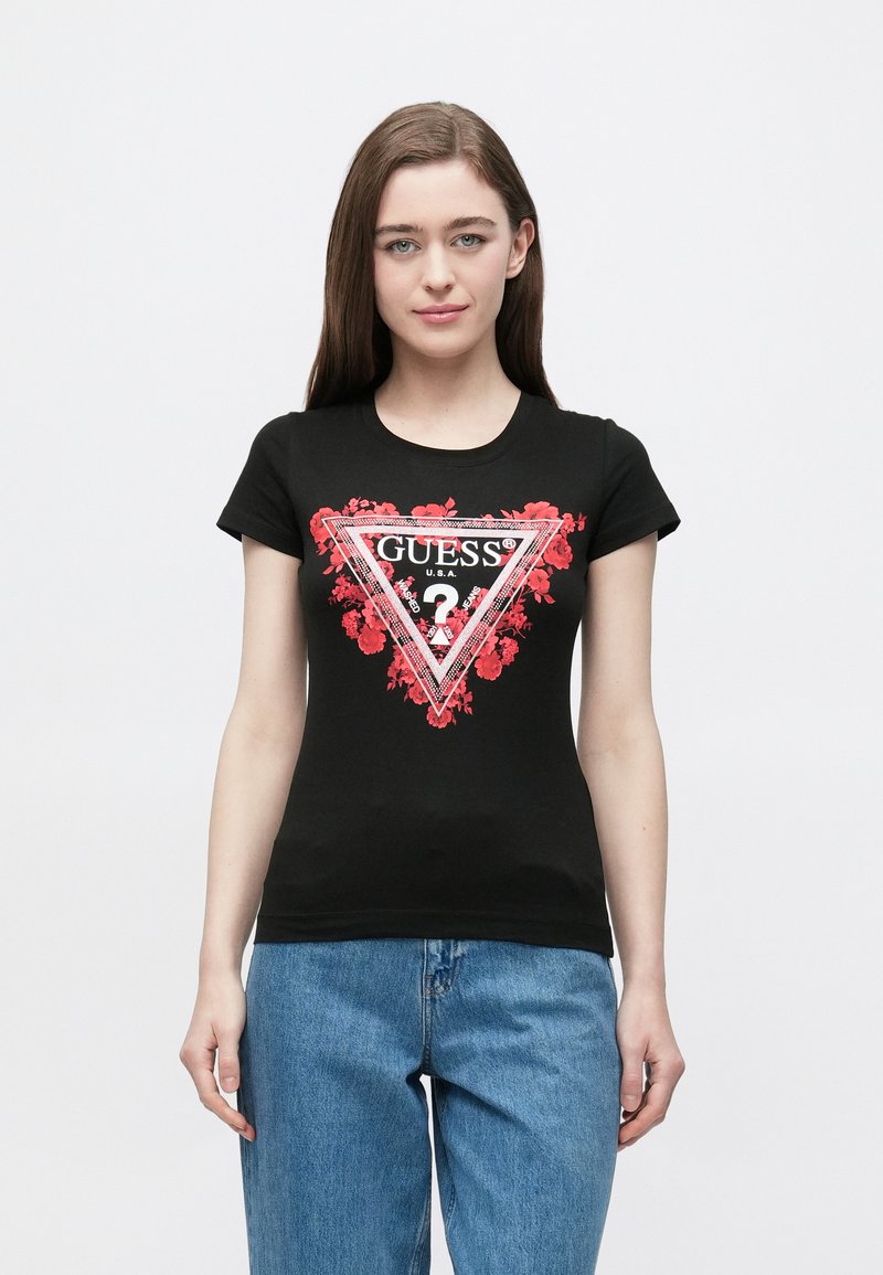 Čierne bavlnené tričko s priliehavým strihom, na ktorom je červený kvetinový trojuholníkový motív a text "GUESS?" v bielej a čiernej farbe v rámci ohraničenia.