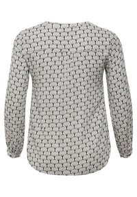 Blouse à manches longues avec un motif de gouttes d'eau noir et blanc répété, poignets élastiqués avec bouton, et ourlet arrondi, vue de dos.