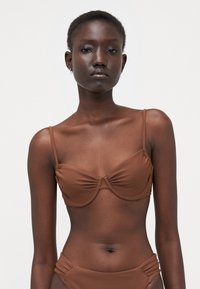 Brun bikini topp med tynne justerbare stropper, med samlet detaljering i midten og en glatt, matt tekstur.