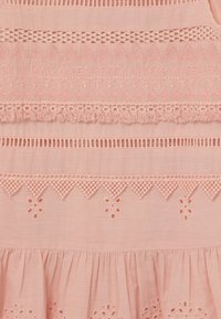 Růžové vyšívané šaty s krajkovým zdobením, vlnitými okraji a květinovými vzory. Měkká látka s texturovaným povrchem a vrstveným designem.