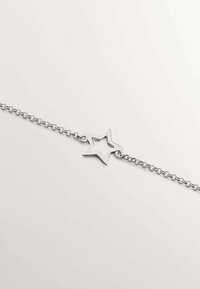 Pulsera de cadena de plata con un colgante en forma de estrella con un centro vacío. Textura suave, diseño minimalista y cierre de gancho estándar.
