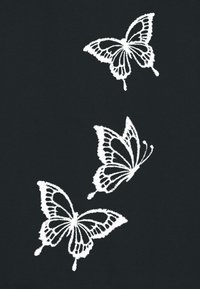 Papillons brodés blancs sur un fond noir, affichant des motifs et textures détaillés des ailes, disposés en agencement diagonal.