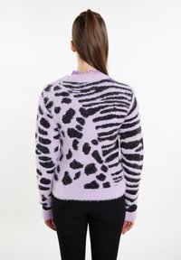 Lila flauschiger Pullover mit schwarzem Tierdruckmuster; lange Ärmel, runder Ausschnitt und strukturierter Stoff; kombiniert mit schwarzen Hosen.