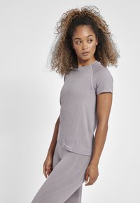 Kortærmet, lyse lilla træningsoverdel med struktureret stof, subtilt mønster og en afslappet pasform, parret med matchende leggings.