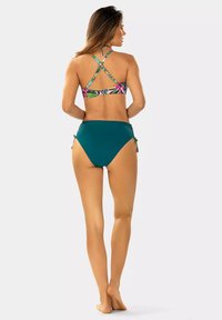 Zestaw bikini z biustonoszem z wielokolorowym motywem kwiatowym, który ma krzyżujące się ramiączka, w połączeniu z jednolitymi, turkusowymi majtkami o wysokim stanie.