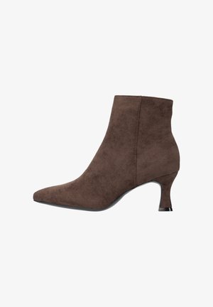 Bottine en daim marron avec bout pointu et talon de hauteur moyenne. Texture lisse et design minimaliste avec des détails de coutures discrètes.