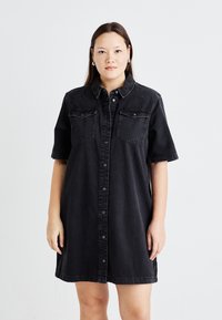 Zwarte denim shirtjurk met korte mouwen, knoopsluiting, puntige kraag en twee borstzakken voor extra detail. Rechstreeks ontwerp.