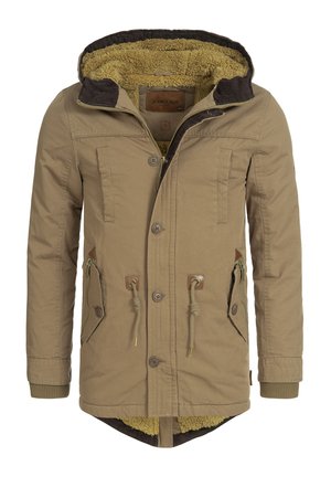 Kaki parka-jakke med hette fôret med sherpa, flere frontlommer, snøring i livet og ribbede mansjetter. Har knapp- og glidelåslukking.