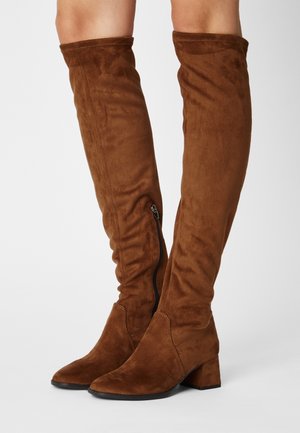Bottes en suède brun, au-dessus du genou, avec un bout pointu et un talon carré, équipées d'une fermeture éclair latérale pour un enfilage facile. Texture lisse et design ajusté.