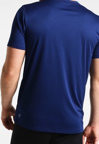 Pánské sportovní tričko s krátkým rukávem v námořnické modré barvě, vyrobené z elasticického materiálu s hladkou texturou, s decentním logem na spodní části.