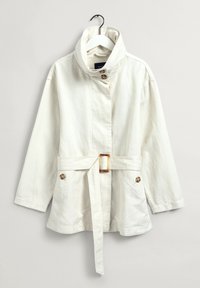 Giacca bianca con colletto alto, due bottoni e vita cinturata. Presenta due tasche frontali e una texture in cotone morbido.